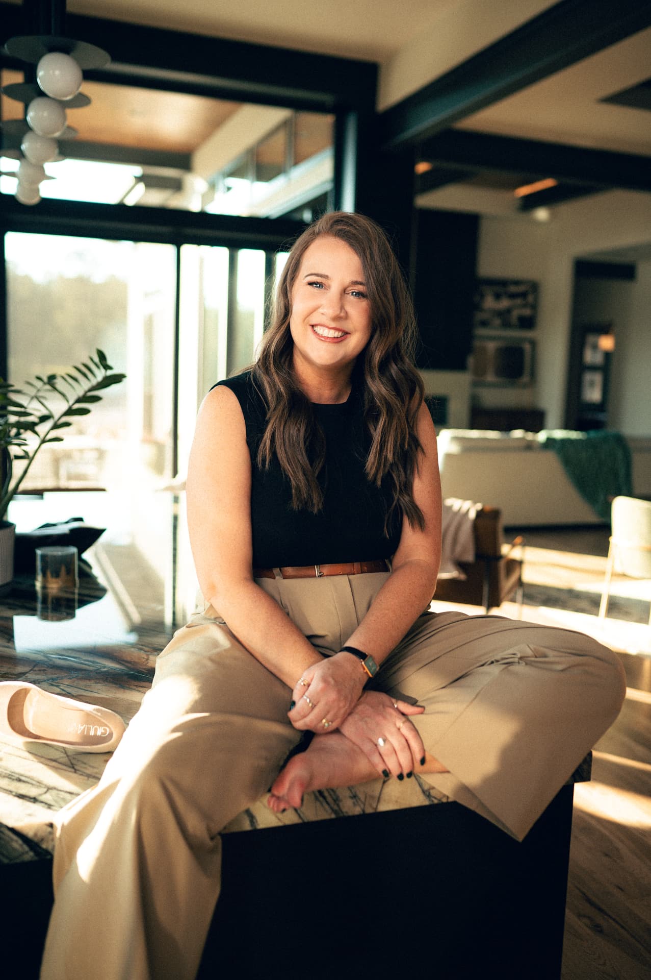 Lindy Denny seated on a stone island in a modern custom home