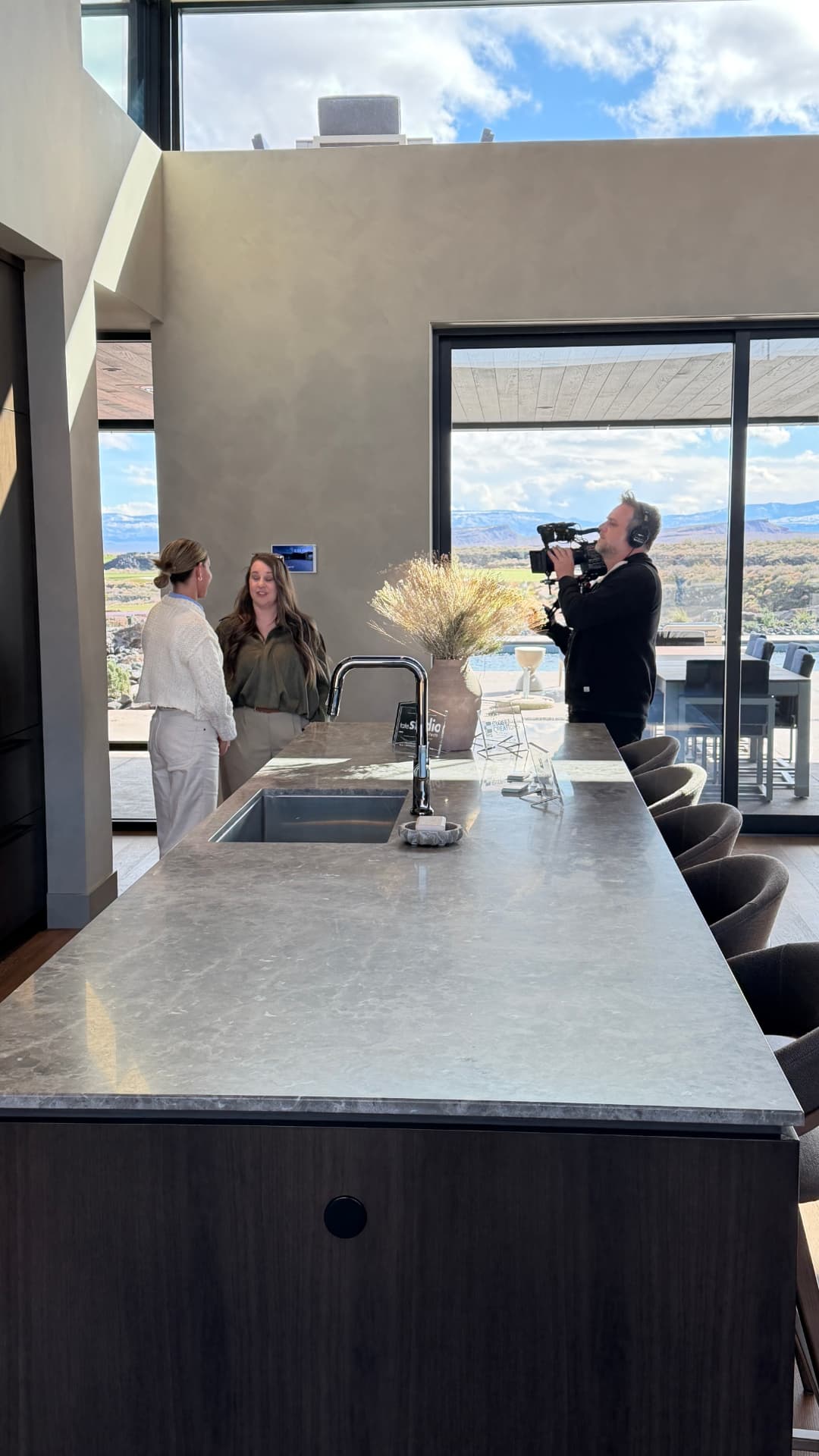 A camera operator filming a walk-and-talk tour in a desert modern kitchen